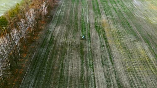 Aerial View Agricultural Tractor Plows a Field at Sunset
