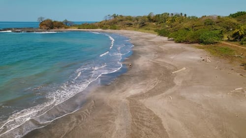 Person walking along a peaceful tropical beach with rainforest in Costa Rica