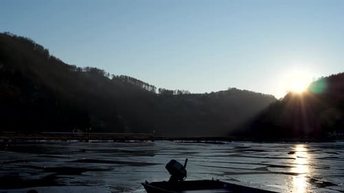 Sunset at the danube river in winter. Ice floes drifting in a harbour. In the foregorund is a lonsom