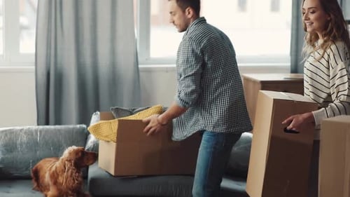 A Couple Joyfully Unpacking Boxes Together in Their Spacious and Inviting Living Area