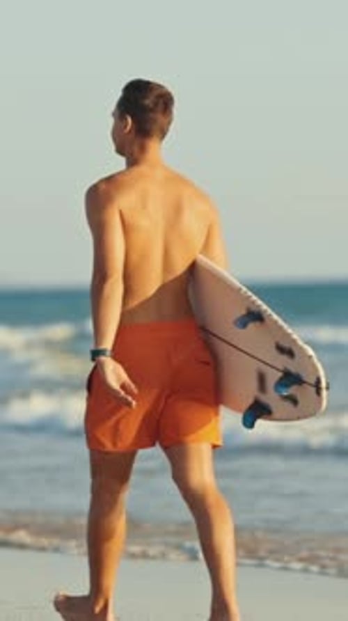 Surfista caminhando na praia com prancha