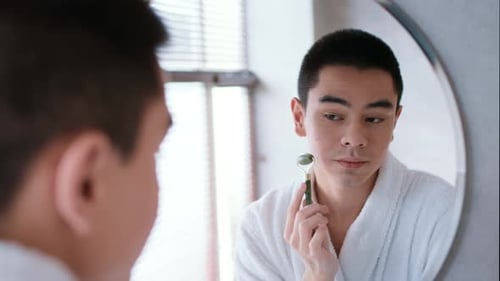 Man in Robe Using Jade Roller for Skincare