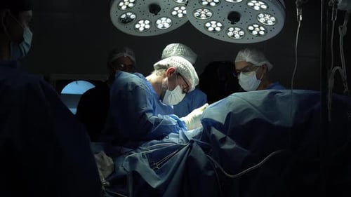 Chirurgen führen eine komplexe Operation unter hellem Operationslicht durch