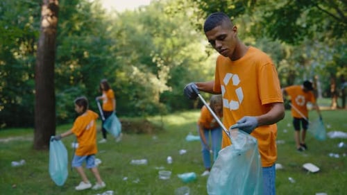 Group of Diverse Volunteers In TShirts with Recycling Symbol Cleaning Up the Public Park Multiethnic