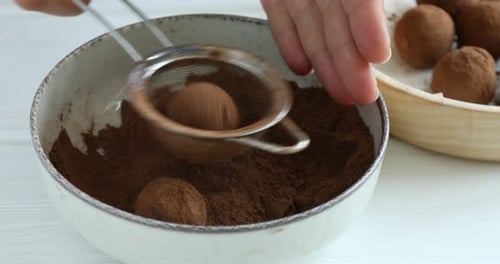 Woman making homemade candies at white wooden table, closeup