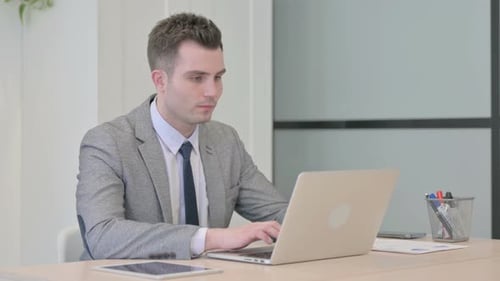 Young Businessman Typing on Laptop in Office