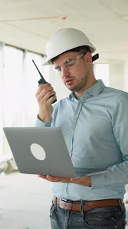 Construction Engineer Using Laptop and Radio on Job Site
