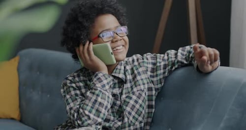 Boy Talking on Smartphone Indoors on Sofa