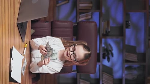 Girl Counting Money and Smiling at Desk