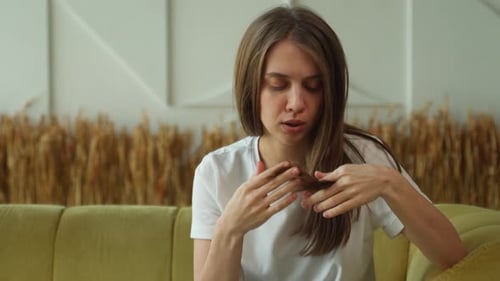 Young Woman Examining Her Hair at Home