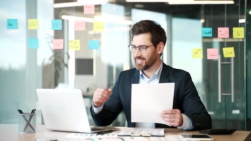 Happy financier satisfied with financial results sitting at workplace in business office