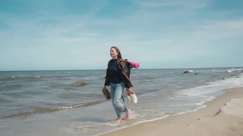 Traveler walks along seashore with backpack