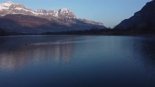 Aerial over the Passy lake early in the morning, with some ducks enjoying the very cold water