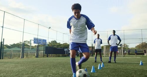 Young Soccer Players Dribbling Ball Around Cones