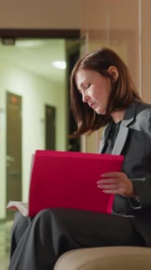 Businesswoman Reviewing Documents Alone in Office Corridor