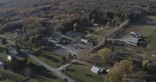Drone aerial clip of a beautiful farmland property with a large pond, forest and a bunch of old buil