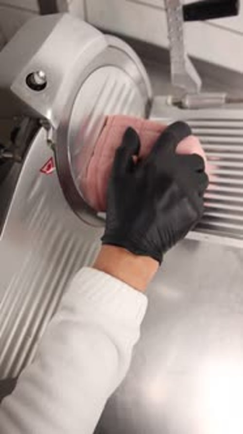 Slicing Delicious Ham with Meat Slicer in Kitchen