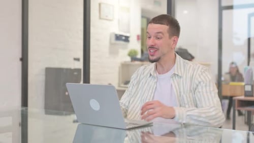 Man Celebrates While Using Laptop in Office
