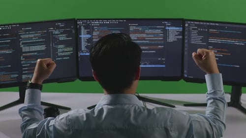 Happy Man Celebrating And Dancing While Write Code With Multiple Computer Screens In Green Screen