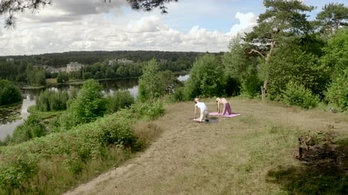 Man and Woman Practice Yoga Camel Pose on Steep River Bank