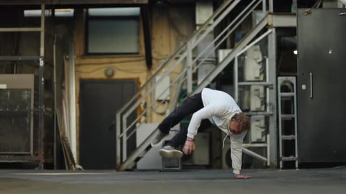 Street Dancer in a White Hoodie Transitions From Walking to a Low Breakdance Floor Move Against an