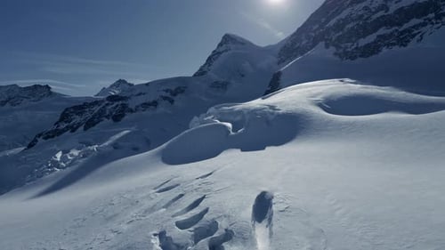 Navigiere durch eine ruhige verschneite alpine Berglandschaft mit Fußabdrücken im Schnee
