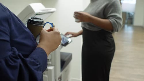 Empresarias con café usando fotocopiadora en la oficina: 25-29 años