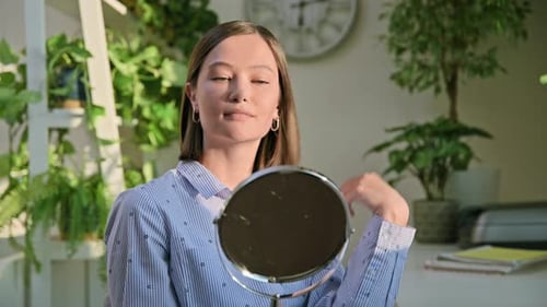 Young Woman Adjusts Hair In Front of Mirror