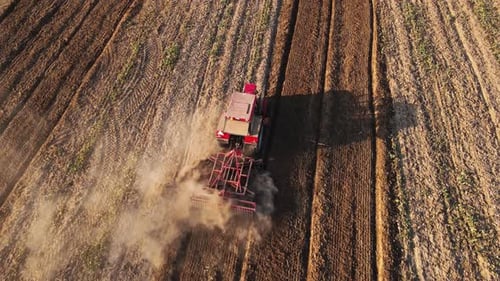 Tractor Working in Agricultural Field Cultivating and Plowing Dry Soil