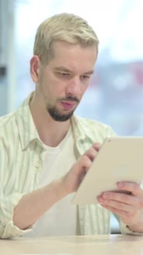Young Man Browsing Internet on Tablet in Office