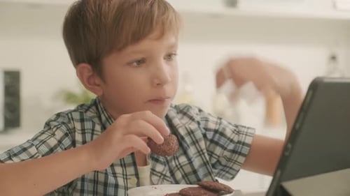 Boy Eating Cookies, Using Tablet in Kitchen