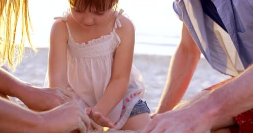 4k-Videomaterial eines kleinen Mädchens und ihrer Eltern, die zusammen im Sand am Strand spielen