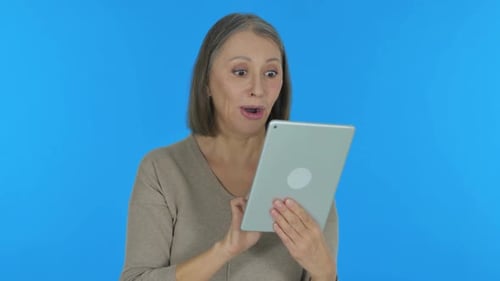Senior Woman Celebrates Good News on Tablet
