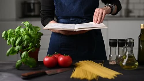 Femme dans la cuisine lisant un livre de reçus dans la cuisine