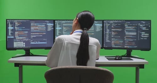 Asian Woman Developer Thinking While Write Code With Multiple Screens In Green Screen Studio