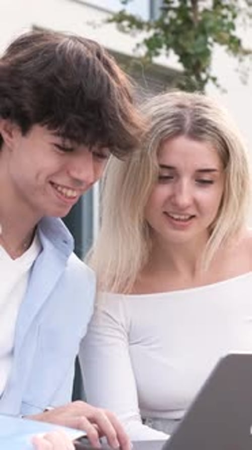 Young Adults Looking at Laptop Outside