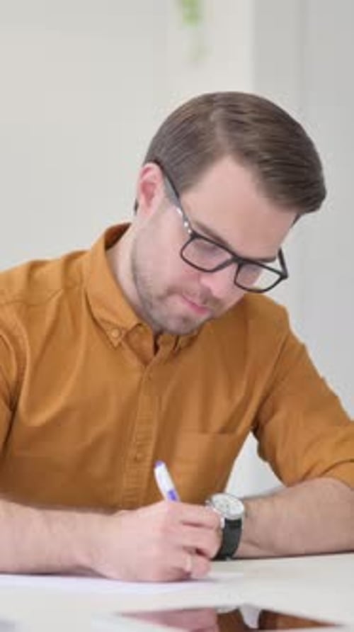 Young Man Writing on Paper in Office, Vertical Video