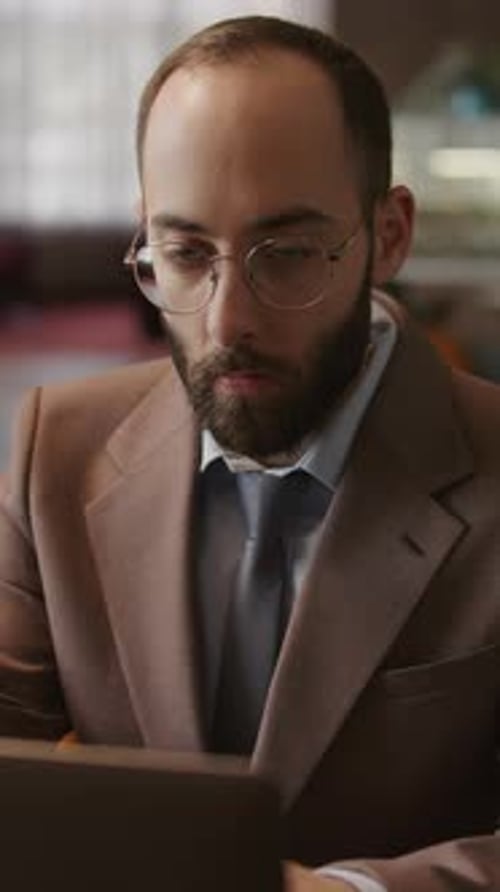 Bearded Male Entrepreneur Working Remotely on Laptop in Cafe