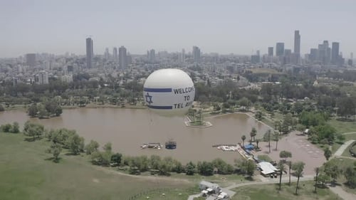 Aerial Shot Of Hot Air Balloon Descending Over Yarkon Park Against Sky In City