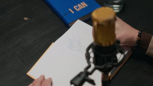 Writing on Notepad Next to Microphone at Desk