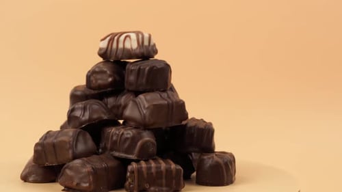 Chocolate candies rotate on an orange background.