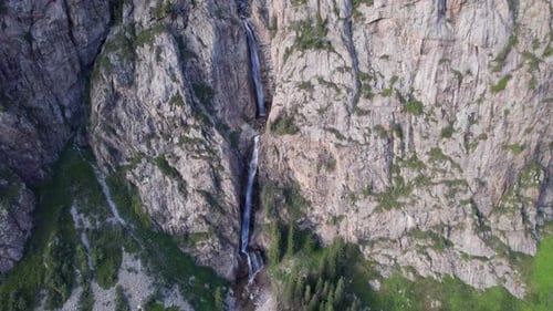 A High Waterfall Cascades in a Mountain Gorge