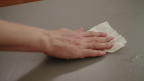 Haushälterin, männlich, wischt mit einem Lappen Wasser vom Tisch ab und sorgt für Sauberkeit und Hygiene im Haushalt