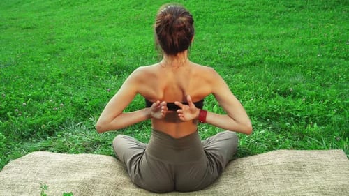 Girl is Sitting on a Yoga Mat Gracefully Performing a Yoga Pose