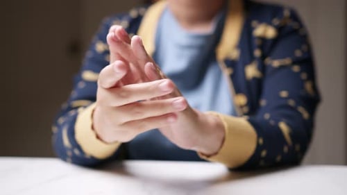 Hands Rubbing Together at a Table Indoors