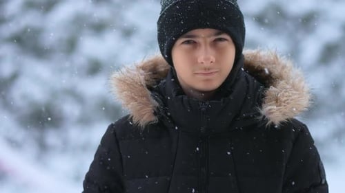 Close Up View of Young Boy Standing in Forest Area in Cold Day During Snowfall
