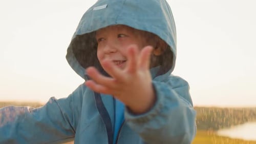 Child Enjoys Rain Shower in Golden Sunlight