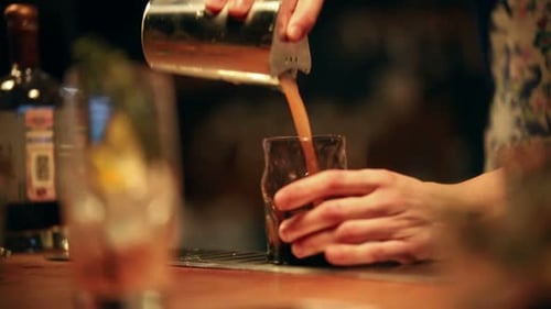 Camarero trabajando mezclando un cóctel alcohólico añadiendo jugo del