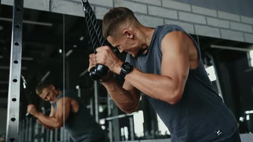Focused Man Exercising with Cable Machine at the Gym for Upper Body Strength