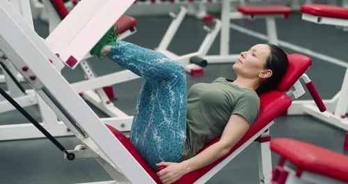Woman Using Leg Press Machine at the Gym